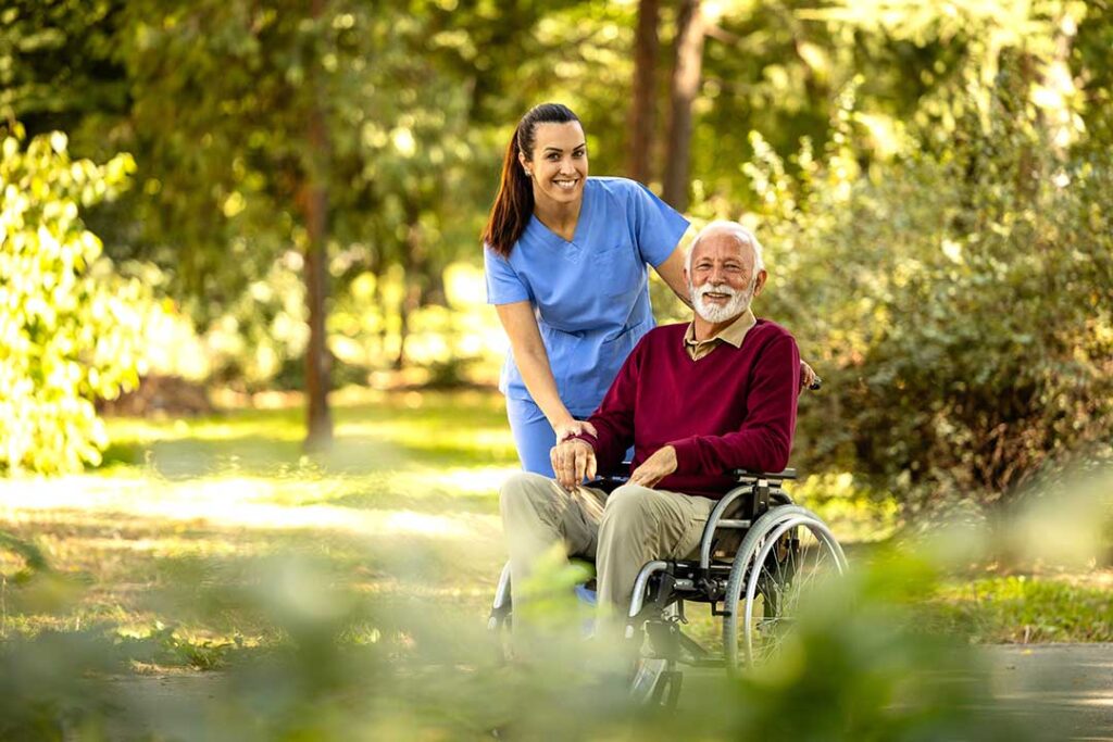 Older adults walking together indoors in an assisted living community with supportive handrails and bright natural light.